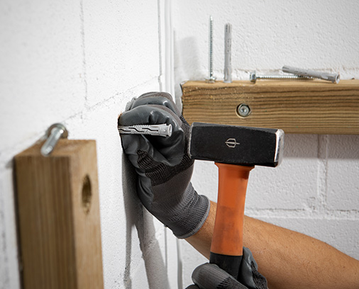 Operator inserting T-NUX plug into wall with hammer